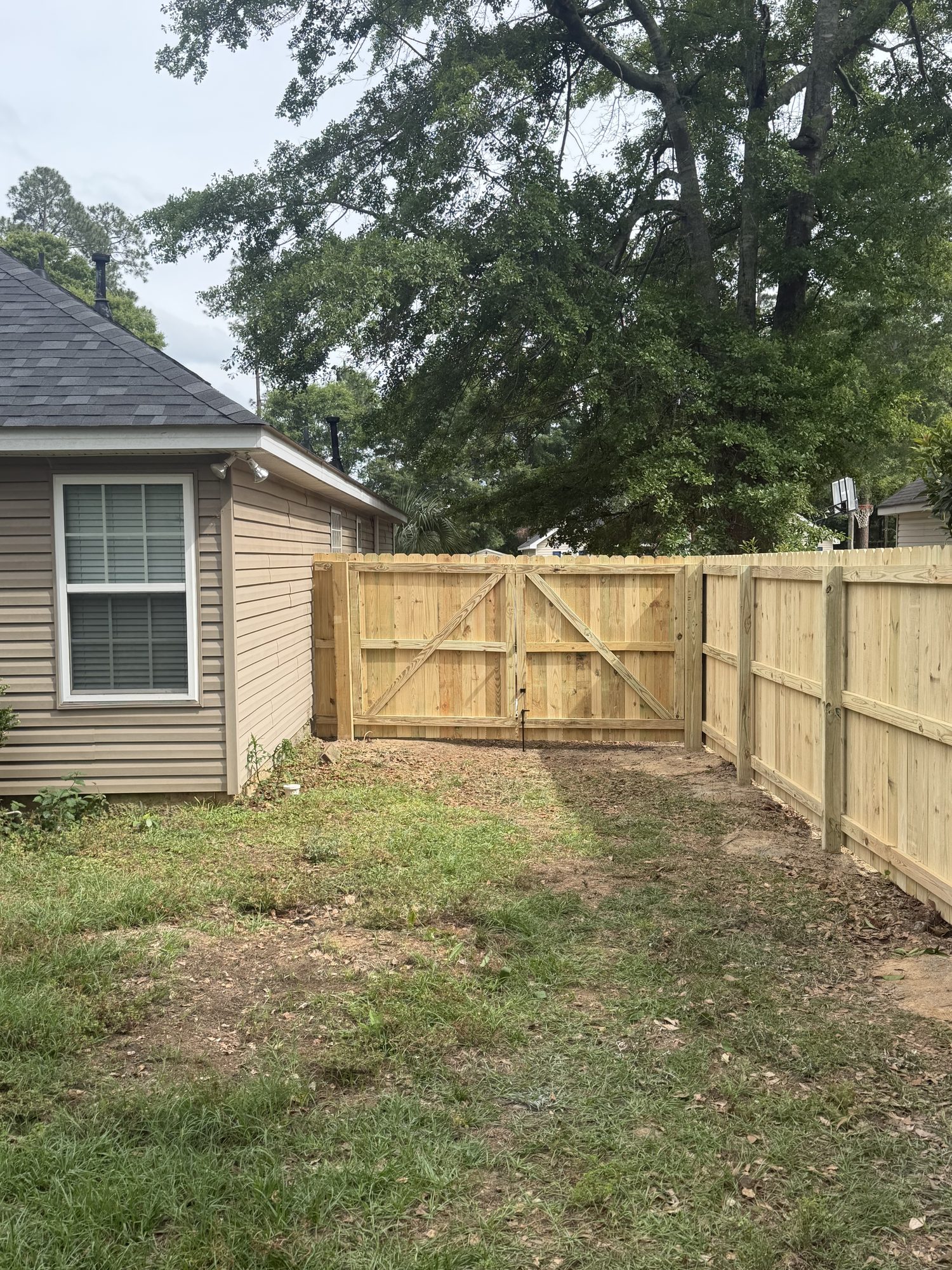 Natural pine wood privacy fence with centered double gate installed around residential backyard in Aiken area.