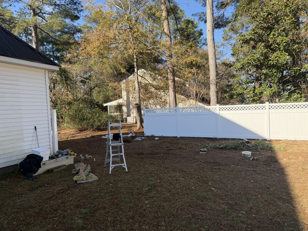 White vinyl privacy fence with lattice top installed beside a home