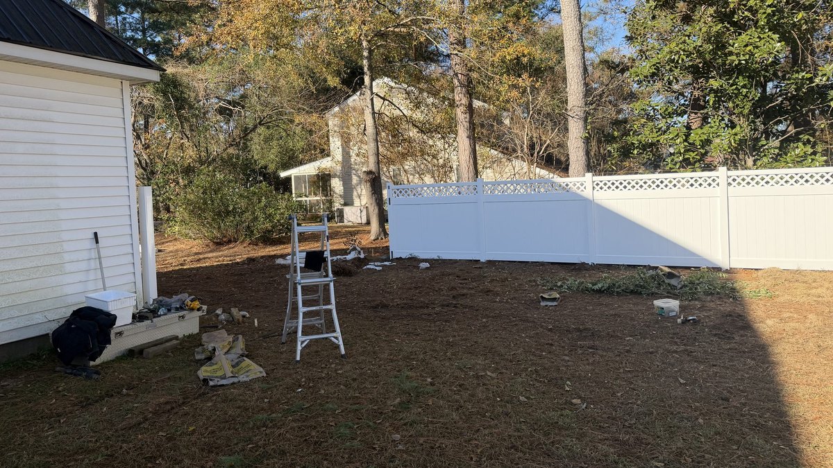 White vinyl privacy fence with lattice top installed beside a home