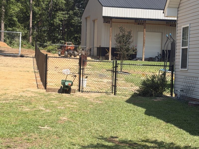 Brown chain-link fence enclosure securing farm equipment storage around rural residential property in CSRA.