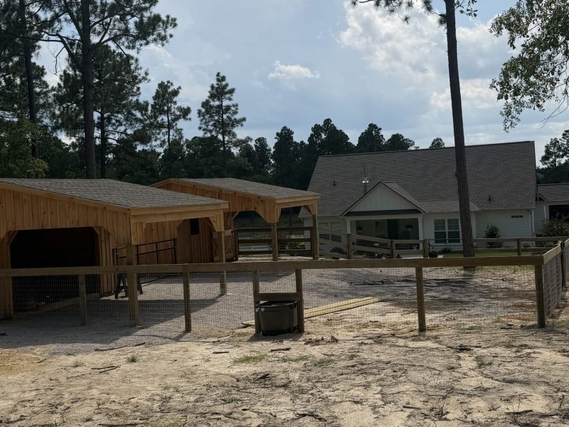 Custom wood fence installation securing paddocks on an active horse farm in the CSRA with barn and arena facilities.