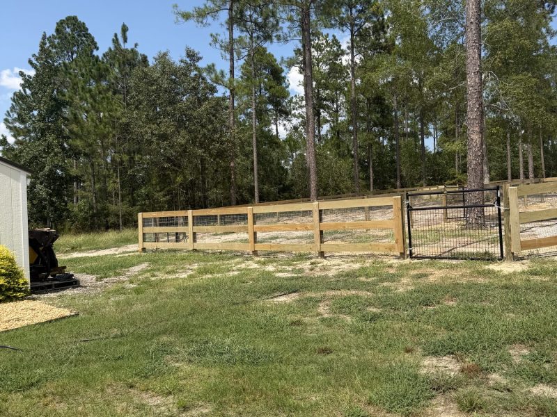 Horizontal wood ranch fencing with metal mesh gates securing rural property in CSRA area.