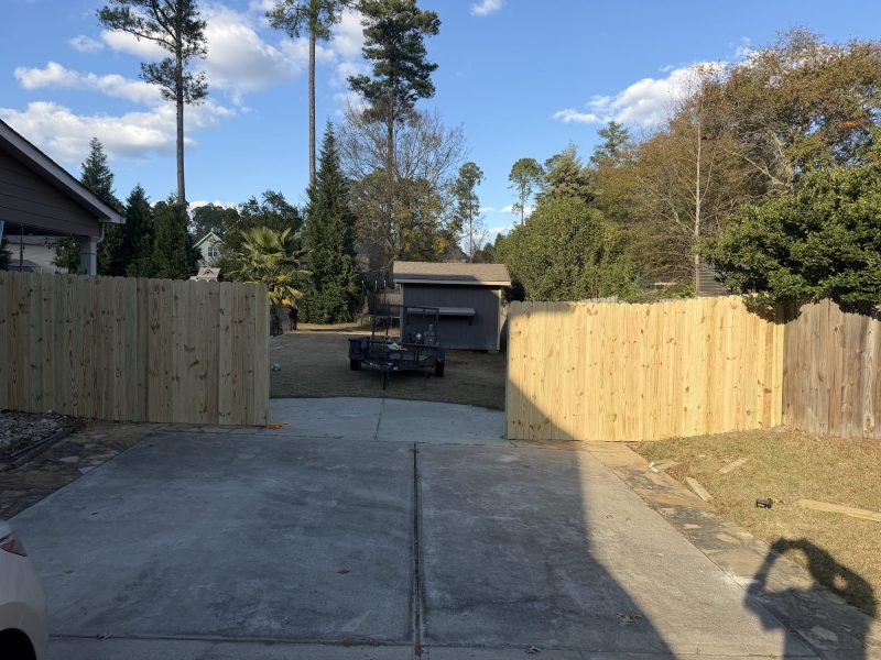 Newly installed wood privacy fence with vertical boards flanking residential driveway in Aiken area.