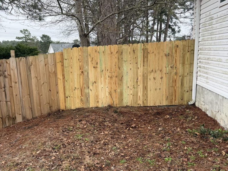 New pressure-treated wood privacy fence installation in honey-colored pine with finished grading around a residential property in the CSRA.
