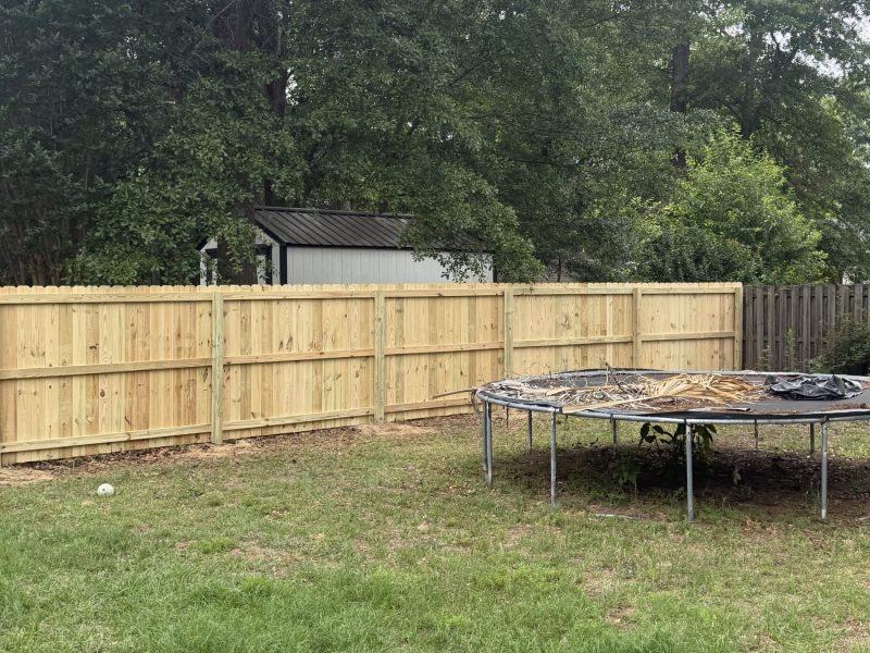 Newly installed horizontal wood privacy fence with natural tan boards securing residential backyard in wooded CSRA setting.