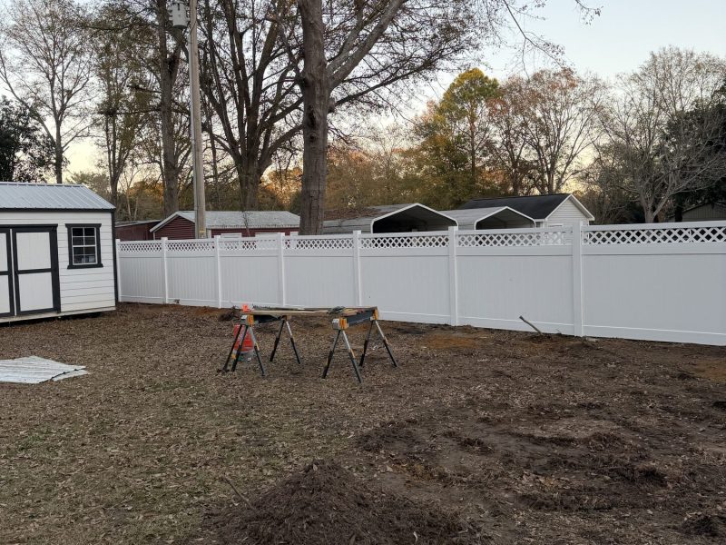 Newly installed white vinyl privacy fence with decorative lattice trim in a residential Aiken County backyard.