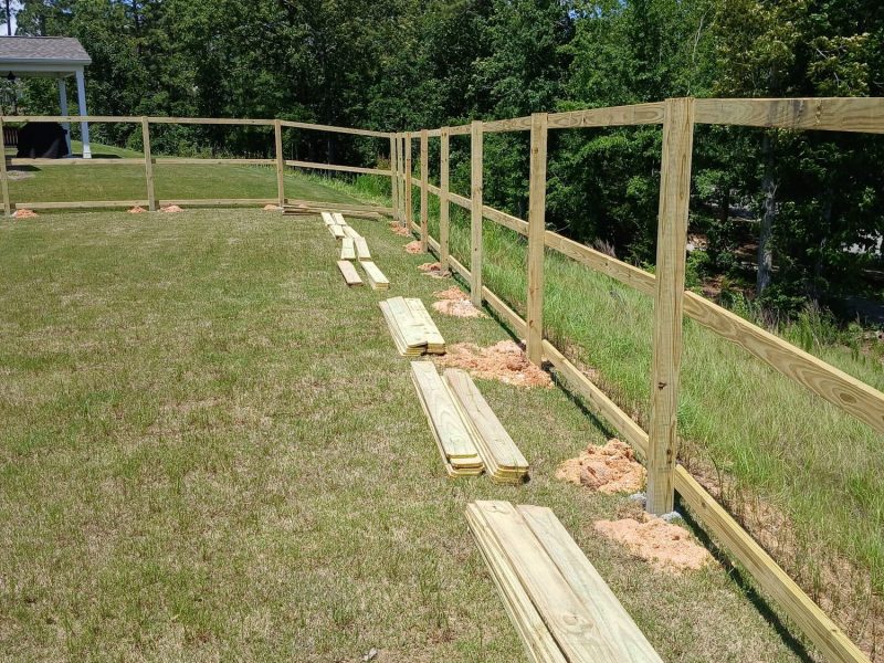 Newly installed wood privacy fence with horizontal rails and posts under construction in residential yard.