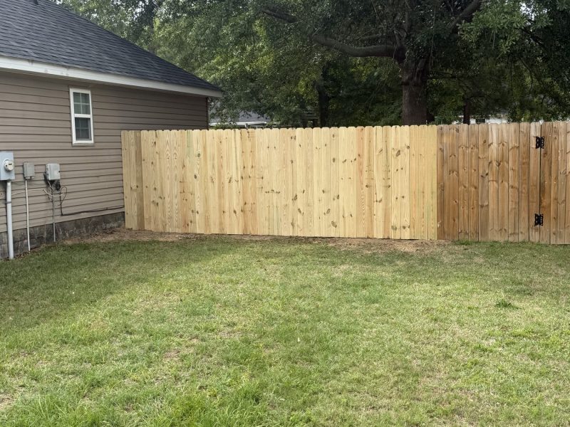 Newly installed wood privacy fence with light-colored cedar boards running along residential back property line in CSRA area.