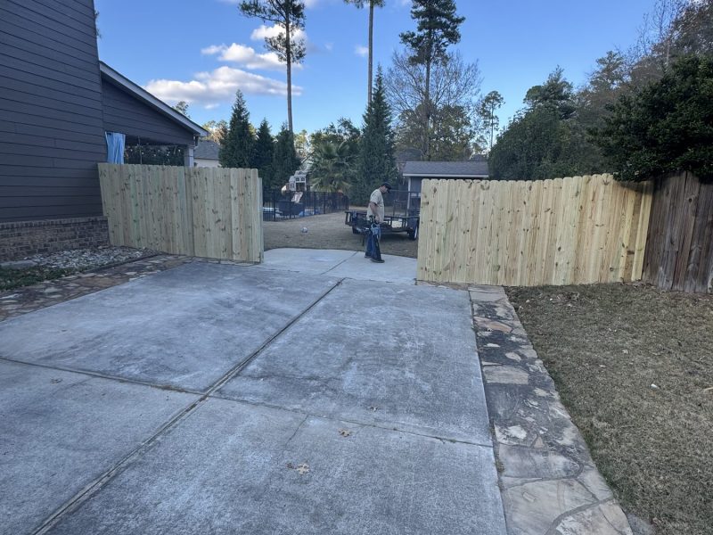 Newly installed wood privacy fence with tan vertical slats flanking residential driveway entrance in Aiken SC area.