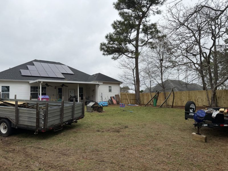 Residential backyard with wood privacy fence installation surrounding property with house and stored equipment.