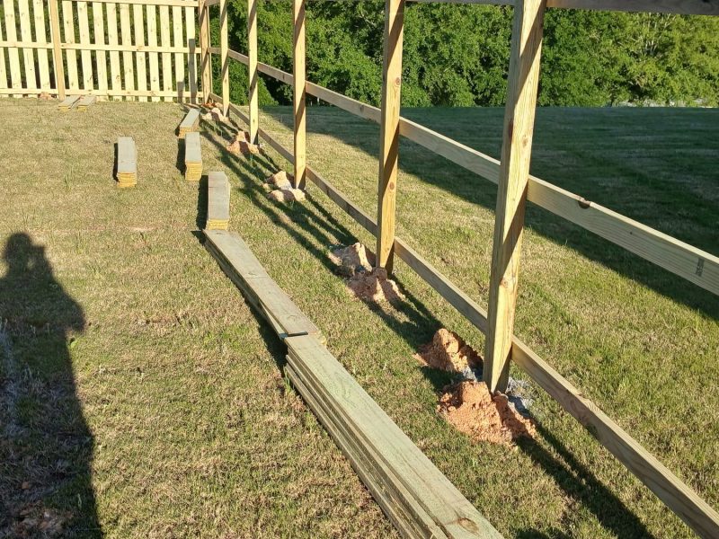 Residential wood privacy fence installation showing vertical slat panels on concrete footings with completed sections visible in the CSRA yard.