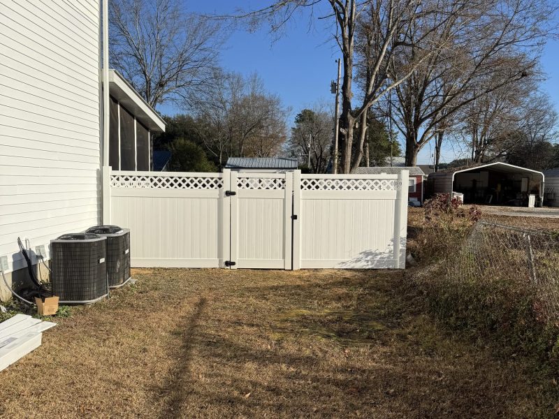 White vinyl privacy fence with lattice topping and matching gate installed in residential backyard by Prime Fencing LLC.