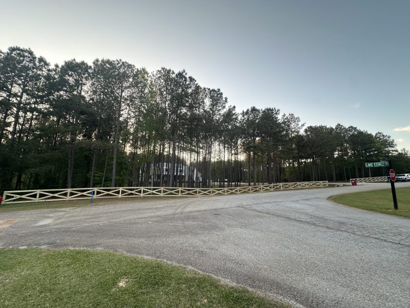 White wood privacy fence lining residential estate driveway in Aiken County with manicured landscaping.
