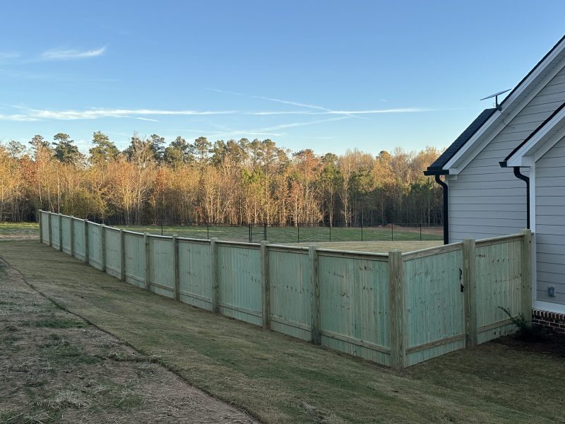 Wood farm fence with green panels and metal rails securing a livestock enclosure on a rural Aiken property.