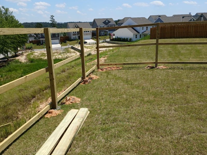 Wood privacy fence installation in progress showing vertical posts and lumber staging at a residential CSRA property.